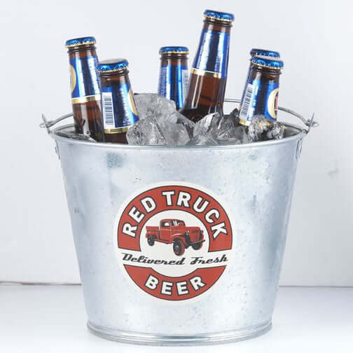 Galvanized metal bucket with ice and beer bottles, featuring a vintage Red Truck Beer logo.