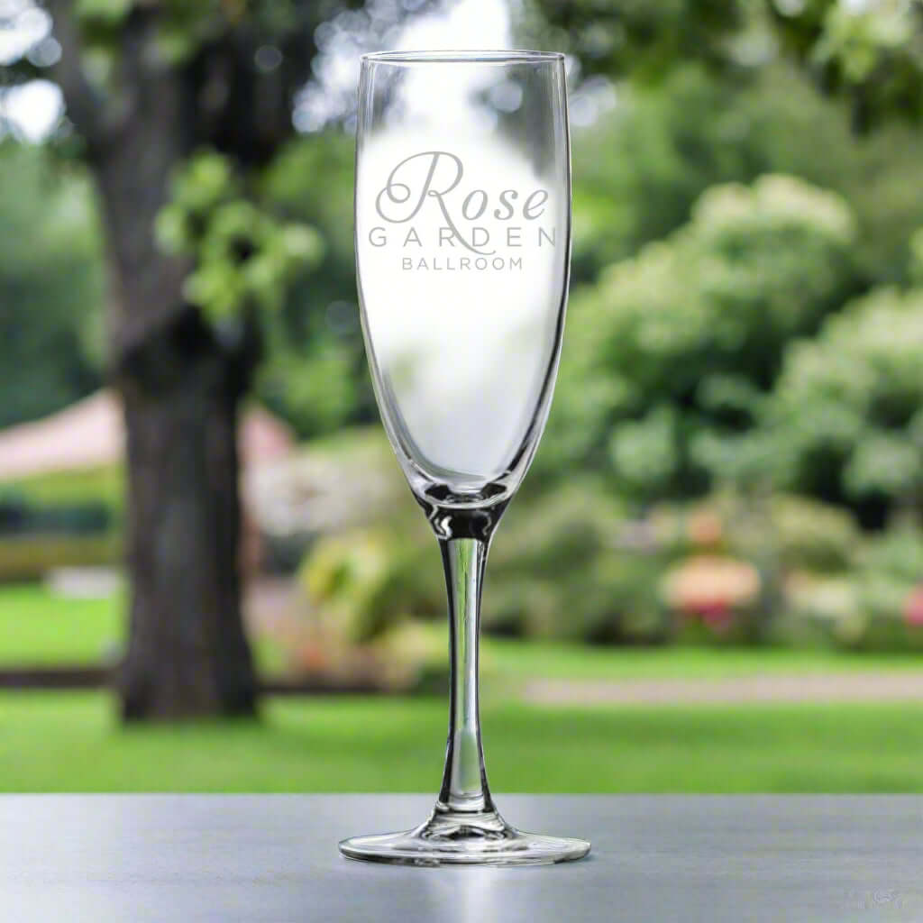 Custom Arc 5.75 oz Nuance Flute Wine Glass with Rose Garden Ballroom branding in a garden setting.