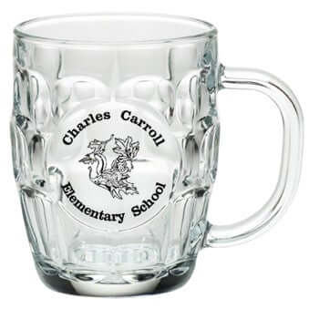 Angled view of empty clear 20 oz Britannia glass mug showing dimpled panel pattern, round smooth imprint panel, and curved handle
