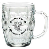 Angled view of empty clear 20 oz Britannia glass mug showing dimpled panel pattern, round smooth imprint panel, and curved handle
